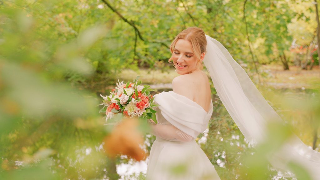 Braut lächelnd zwischen Bäumen a, Teich.